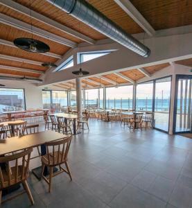 a dining room with tables and chairs and windows at Hostal Náutico de Razo in Carballo