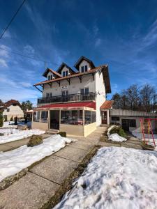 a large white house with snow on the ground at Apartmani Vita in Divčibare