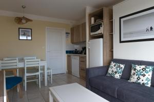 a living room with a couch and a table at Les Sables-d'Olonne - Vue Mer, Terrasse, Wifi Fibre & Piscine, à 2 pas de l'Océan - E101 in Les Sables-d'Olonne
