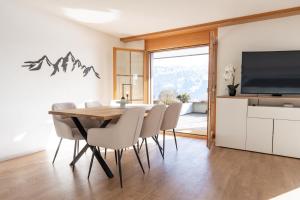 a dining room with a table and chairs and a television at Alpenblick in Beatenberg