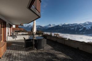 a patio with a table and an umbrella and mountains at Alpenblick in Beatenberg