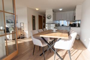 a kitchen and dining room with a wooden table and white chairs at Alpenblick in Beatenberg