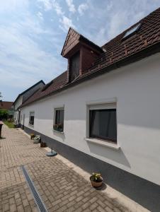 a white building with windows and a brick sidewalk at Lindo - Historisches Hof-Juwel in Schützen am Gebirge