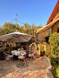 a table and chairs with an umbrella on a patio at Family PlayHouse - Villa Mitsi Sarande in Sarandë