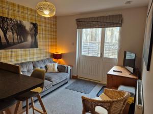 a living room with a couch and a tv at The Studio in Drumnadrochit