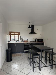 a kitchen with a black table and some chairs at Appartement Maisonnette pour 4 personnes in La Ferté-Vidame