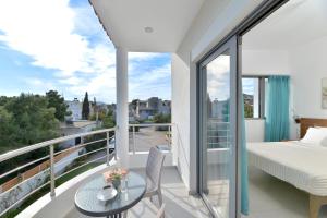 a bedroom with a balcony with a bed and a table at SunDay Free Airport Shuttle in Artemida