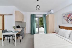 a bedroom with a bed and a table and a kitchen at SunDay Free Airport Shuttle in Artemida