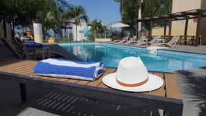 Ein Hut und ein Handtuch liegen auf einem Tisch neben einem Schwimmbecken. in der Unterkunft Zar Manzanillo in Manzanillo
