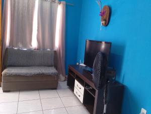 a living room with a tv and a chair at Casa condomínio clube in Araruama