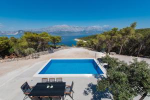 a swimming pool with a table and chairs and a lake at Villa Maris in Povlja