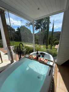 a bath tub with a view of a garden at Cabana Branca luxo in Teresópolis