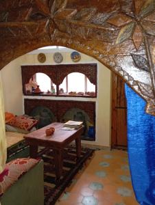 a living room with a table and a fireplace at Maison d hôtes Tioute Chez Abdelmajid in Tiout