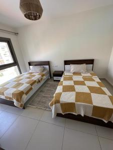 a bedroom with two beds and a window at Marina Marassi in El Alamein