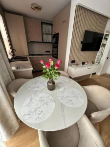 a white dining room table with pink flowers on it at Sara Home in Baia Mare
