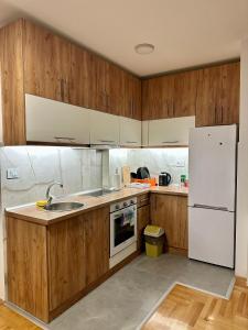 a kitchen with wooden cabinets and a white refrigerator at Vidolux Studio - Free Garage and Fast WiFi in Niš