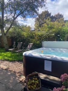 a hot tub in a yard with a bowl of fruit at The Nookery in Winscombe