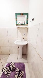 a bathroom with a sink and a mirror and a purple rug at paraiso da lagoa in Imbituba +11 photos