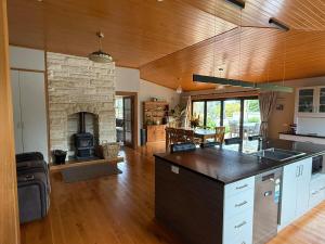 a large kitchen with a stone fireplace in a living room at Rakanui Hidden Retreat in Hilderthorpe