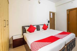 a bedroom with a large bed with red pillows at Hotel O Sagar Comforts in Bangalore
