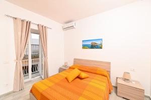 a bedroom with a bed with an orange blanket at La Perla Sul Mare in Forio d'Ischia