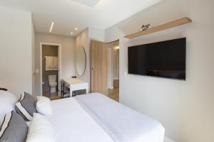 a bedroom with a white bed and a flat screen tv at Elegante Apartamento no Cambuí in Campinas +9 photos