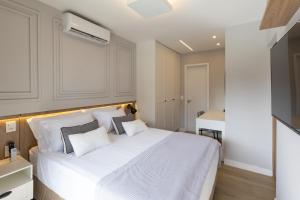 a bedroom with a large white bed with two pillows at Elegante Apartamento no Cambuí in Campinas