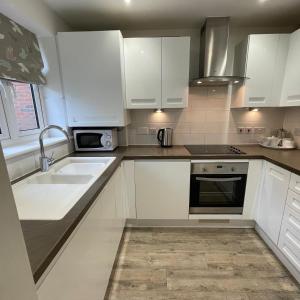 a kitchen with white cabinets and a sink at Rock Lobster in Camber