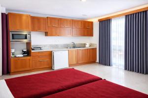 a kitchen with wooden cabinets and a red rug at Oasis Apartments & Rooms in Plakias