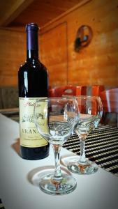 a bottle of wine and two wine glasses on a table at Mountain House Jelovica in Berane