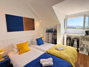a bedroom with two beds with yellow and blue pillows at Naval Guest House in Vila do Conde