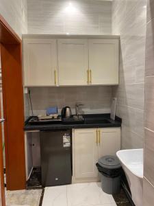 a small kitchen with white cabinets and a sink at كيان الين in Muhayil +14 photos