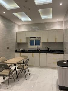 a kitchen with white cabinets and a table and chairs at كيان الين in Muhayil