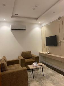 a living room with a couch and a tv and a table at كيان الين in Muhayil