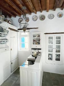 a kitchen with white cabinets and plates on the wall at Castle Seaview in Serifos Chora +15 photos