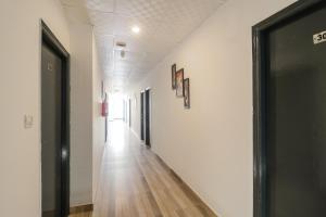 a hallway with white walls and a wooden floor at Hotel O Perky Stay in Faridabad