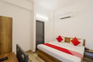 a bedroom with a bed with red pillows at Hotel O Perky Stay in Faridabad +18 photos
