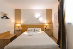a bedroom with a large white bed with two pillows at Hotel Le Coureau in Saint-Trojan-les-Bains +42 photos