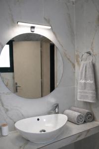 a bathroom with a white sink and a mirror at Adriolos Apartments in Liapades