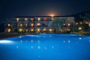 a large blue pool in front of a building at night at Adriolos Apartments in Liapades