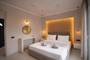 a bedroom with a large white bed with a mirror at Adriolos Apartments in Liapades