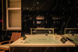 a bath tub in a room with a black wall at Golden Suite - Elegance - Private Spa Jacuzzi in Lens