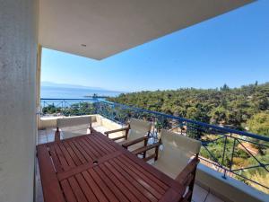 a balcony with a wooden table and chairs and the ocean at Pine Lodge in Kavála