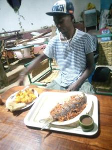 a man sitting at a table with a plate of food at Laminas beach camp in Kilifi
