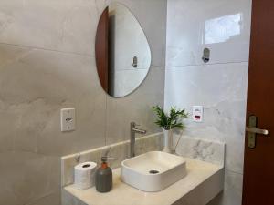 a white bathroom with a sink and a mirror at Suítes Brotas in Brotas +15 photos