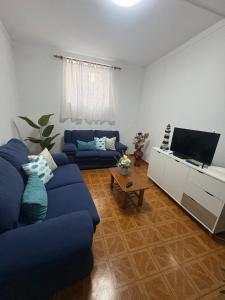a living room with a blue couch and a flat screen tv at Casa São Marcos in Peniche