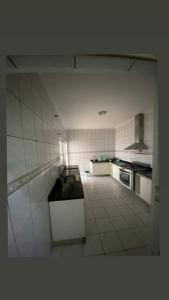 a large white kitchen with a counter in it at Residêncial Allah in Peruíbe