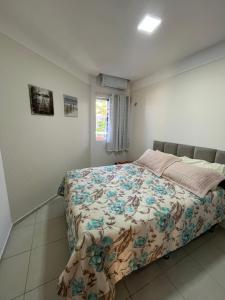 a bedroom with a bed with a floral bedspread at Apartamento Duplex vista mar Buzios in Nísia Floresta +26 photos