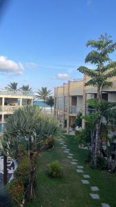 a resort yard with palm trees and a building at Apartamento Duplex vista mar Buzios in Nísia Floresta