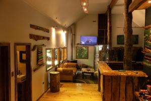 a room with a living room with a tv on the wall at Curahuapi Refugio de Montaña in Las Trancas